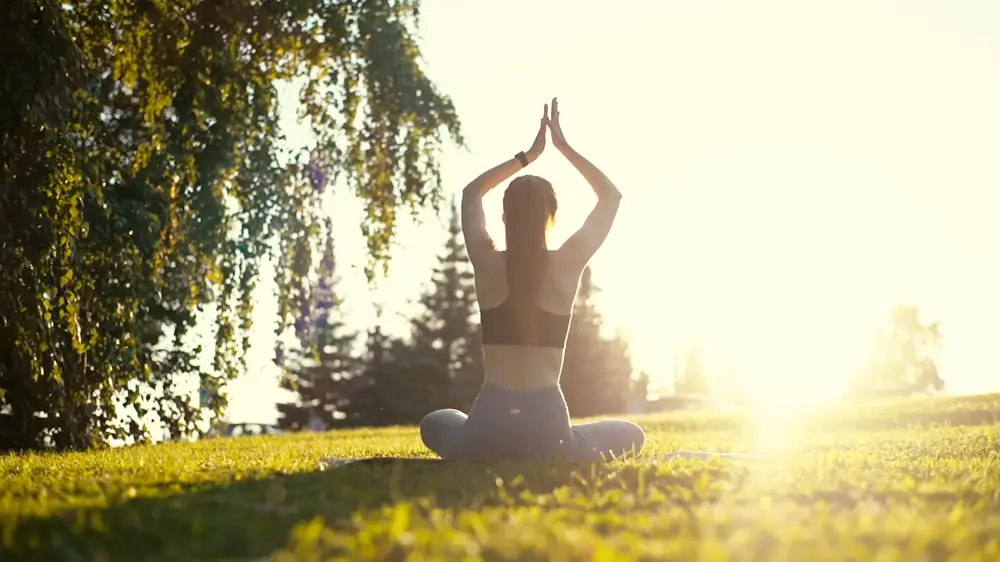 Femme zen faisant du yoga, assise dans un parc, par un temps ensoleillée